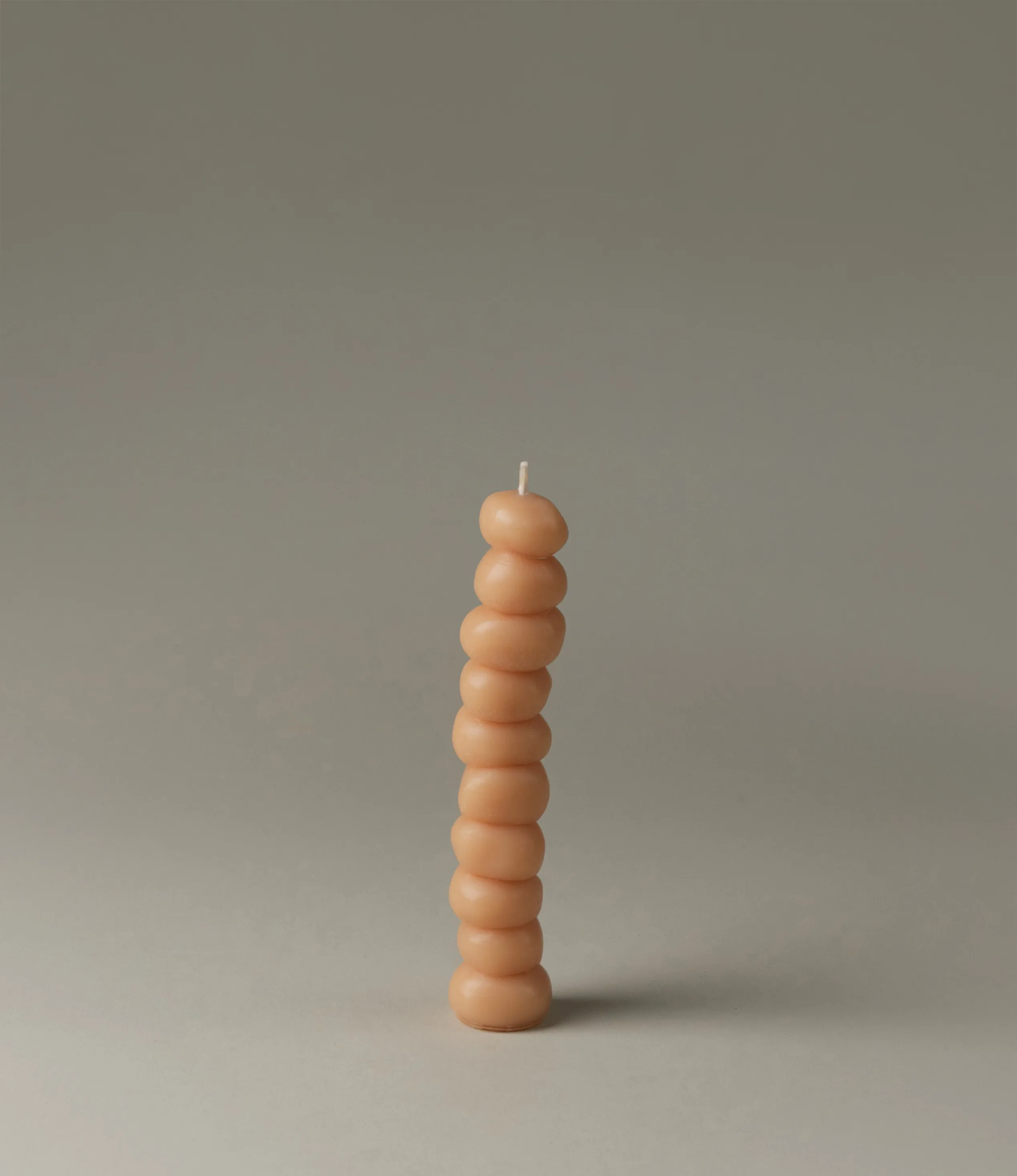Grape Candle from Ann Vincent has the shape of grapes stacked on top of each other. It has a light nude color.