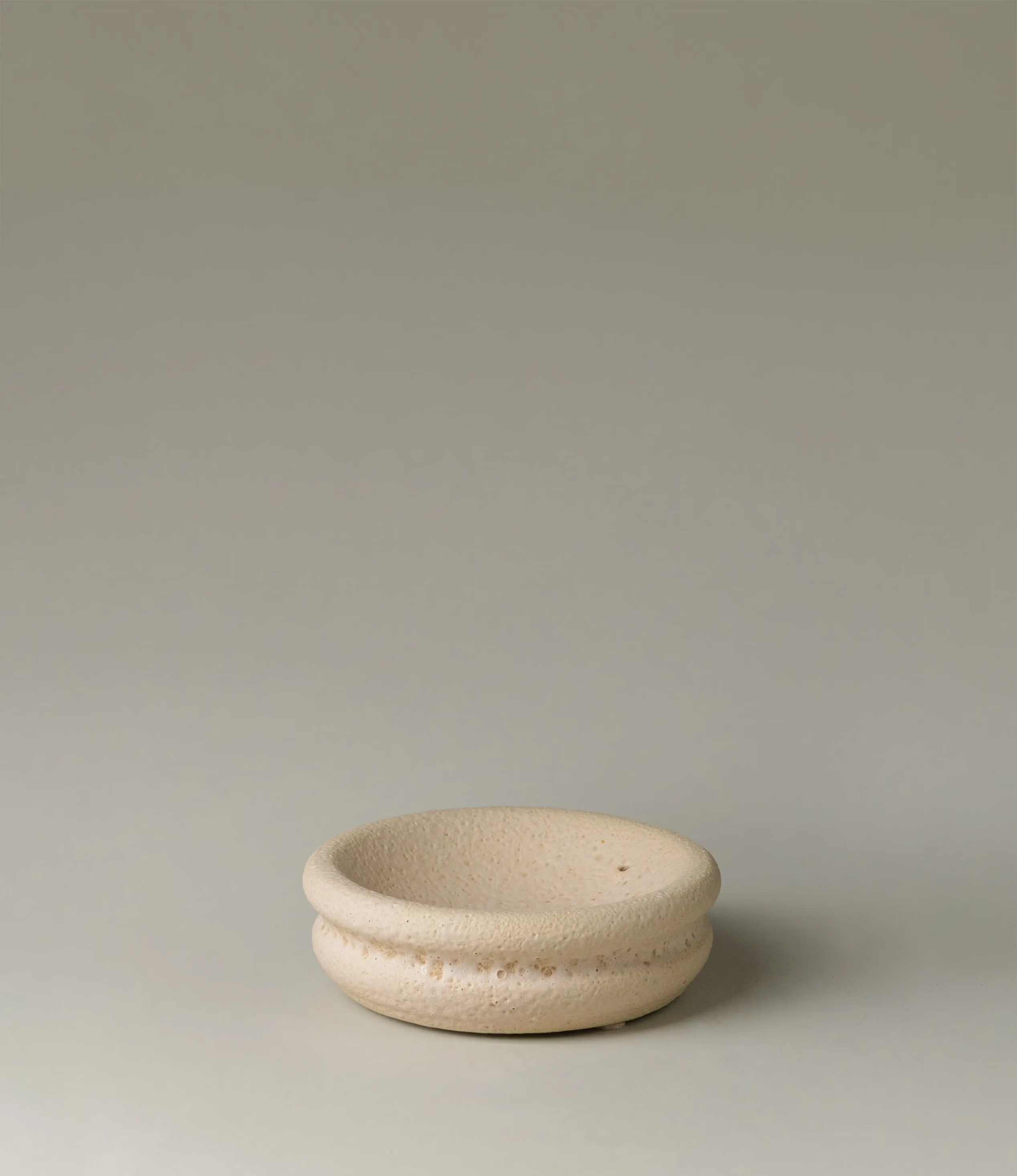Lyot Incense Holder designed by Ocactuu has a sand texture and comes in a light nude color. The rounded plate has the place for your incense close to the edge of it.