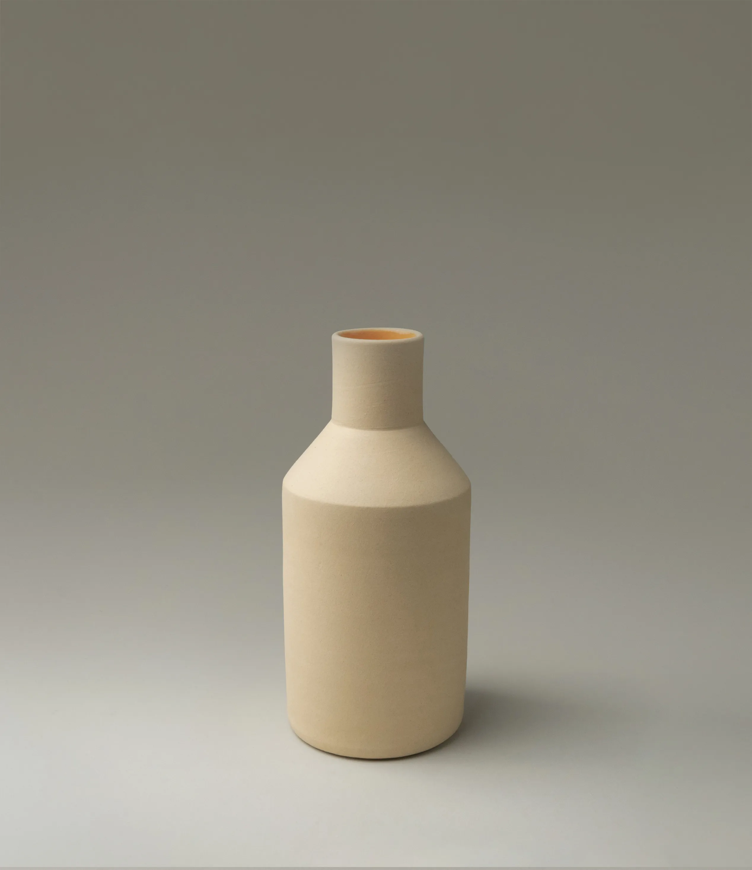 Natural Orange Vase was designed by Ocactuu. The item has a champagne color matte finish on the outside and a bright orange glossy glaze on the inside. The product is very geometrical and it has clear edges.